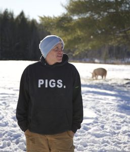 Todd Friedman standing in the snow with a pig in background. (Big Wave Productions)