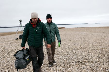 David Reichert and Eric Stackpole walk on the beach in Svalbard with a camera set up behind them to film walrus. (National Geographic/Mario Tadinac)