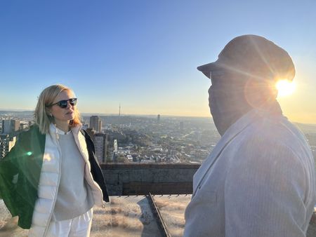 Mariana van Zeller and Ben discuss the world of scamming while on a rooftop in Johannesburg. (National Geographic for Disney)
