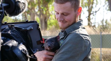 Tyler holding a tasmanian devil baby while being filmed. (Big Wave Productions)