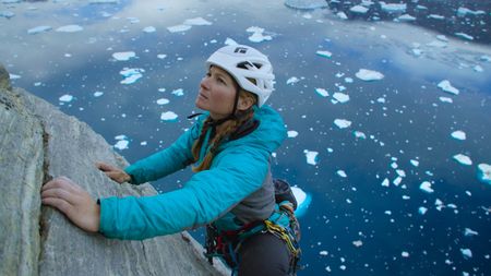 Hazel Findley climbs Ingmikortillaq with icebergs below.  (photo credit: National Geographic/Pablo Durana)