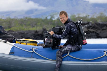 Bertie Gregory in dive gear with an underwater camera sitting on the edge of a small rib preparing to dive. (credit: National Geographic/Zubin Sarosh)