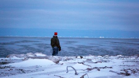 Sue Aikens gathers salt water while standing on the edge of the Arctic Ocean. (BBC Studios/Michael Cheeseman)