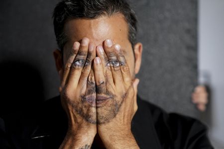 David Blaine poses with his hands painted as his face.  (credit: National Geographic/Dana Hayes)