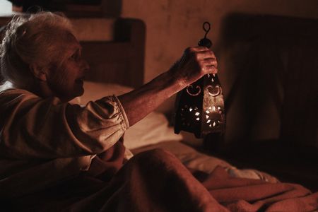 Ann Haltridge sits in bed and holds a lantern. (Dash Productions Services LTD/Antoan Ivanov)