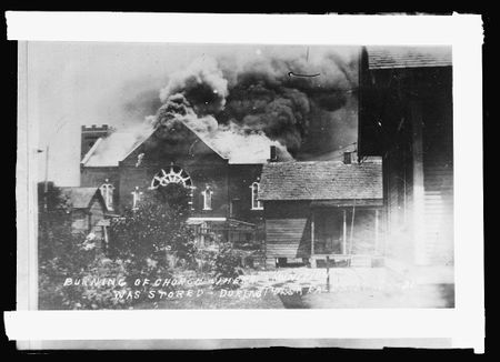 An archival image with the caption "Burning of church where ammunition was stored during race riot, Tulsa, Okla." (Library of Congress)