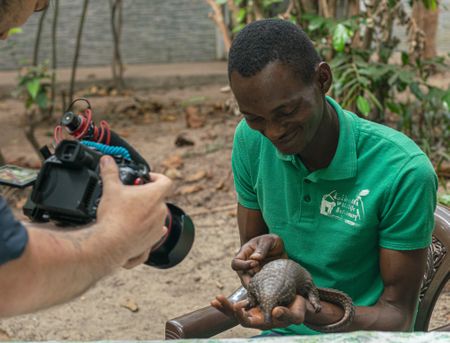 BTS of Beyan Borbor holding Wallah the pangolin. (Big Wave Productions)