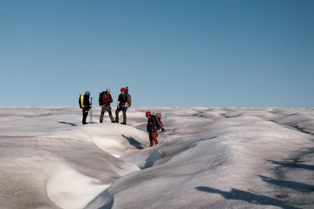Melissa Marquez, Andreas Alexander, PolarX guide Tom Lawton, and PolarX guide Loup Supery hike up a Svalbard glacier. (National Geographic/Mario Tadinac)