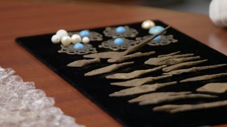 Multiple ancient artifacts, found in a shipment are sitting on an inspection table while a fine art appraiser examines them. (National Geographic)