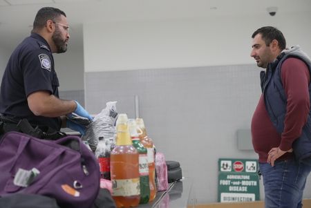 Bottles of homemade wine are seen on an inspection table while CBP Officer De La Cruz questions a traveler and inspects their luggage at the Philadelphia International Airport in Philadelphia, Pa.  (National Geographic)