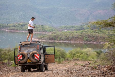 Drone operator Adam Clarke on top of a safari vehicle. (National Geographic for Disney/Maia Sherwood-Rogers)