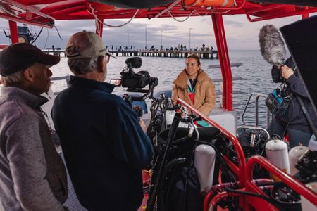 Director and cinematographer, Adam Geiger, and cinematographer, Rory McGuinness, filming an interview with storyteller and cephalopod expert, Dr. Alex Schnell. The team are on board a dive vessel in Port Phillip Bay.   (photo credit: National Geographic/Harriet Spark)