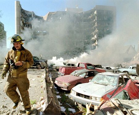 An Oklahoma City fireman walks near explosion-damaged cars on the north side of the Alfred Murrah Federal Building in Oklahoma City after a car bomb explosion on April 19, 1995, in Oklahoma City, Okla. (Jim Argo/USA TODAY Network)