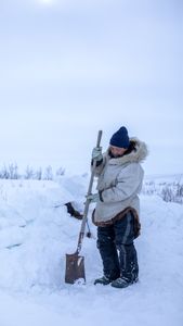 Agnes Hailstone shovels snow to help set up their family camp in Kiwalik. (BBC Studios Reality Productions/Ashton Hurlburt)