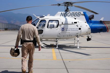 Air Enforcement Agent Murray is holding his helmet as he walks across a tarmac to a CBP air vehicle in San Diego, Calif. (National Geographic)