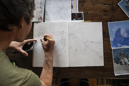 Alex Honnold writing a climbing report of their climb in Dieter Klose's book, including an illustration of the route.  (National Geographic)