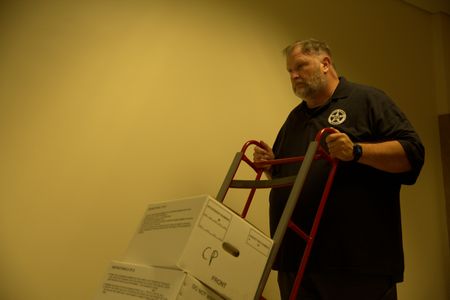 Veteran US Marshal Mark Stroh pushes boxes of documents with a dolly in an image made during the production of "Cursed Gold: A Shipwreck Scandal." In 1989, maverick scientist Tommy Thompson stuns the world by recovering three tons of gold from a shipwreck deep in the Atlantic Ocean. What follows is a 30-year story of adventure, deception, and personal turmoil, taking him from venerated celebrity to infamous fugitive, and finally a defiant prisoner who refuses to give up his gold. (National Geographic)