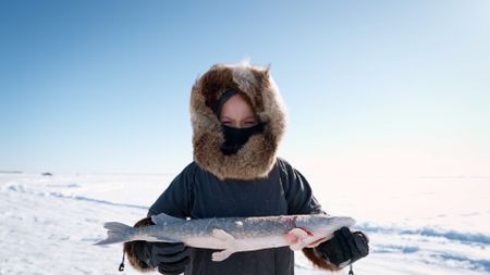 Jaxon Hoffman holds up the pike he caught through the ice. (BBC Studios/Brian Bitterfeld)