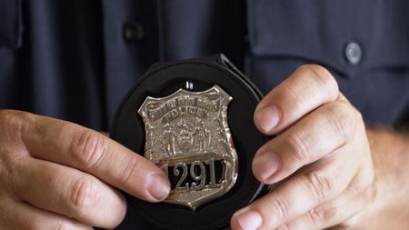 CBP Deputy Chief Canzano holds an authentic-looking, fake police badge found in a shipment in Newark, N.J. (National Geographic)