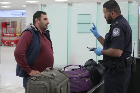 CBP Officer De La Cruz questions a traveler while they inspect the traveler's luggage at the Philadelphia International Airport in Philadelphia, Pa.  (National Geographic)