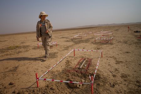 Sinjar, Iraq - Hana Khidera walks by unexploded mines that have been sectioned off in a minefield. (Sean Sutton)