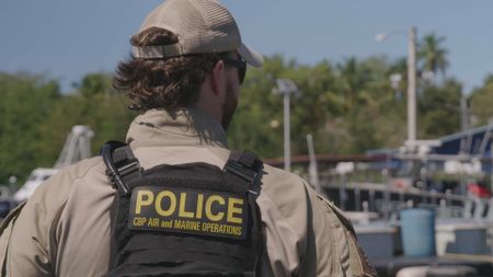 CBP AMO Agent Squires peers over the dock as the crew heads out for their next operation  in Mayaguez, P.R. (Lucky 8 TV/Ivan Leon)