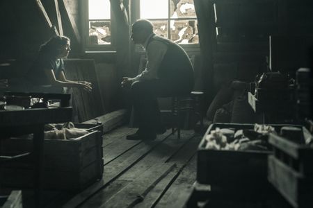 A SMALL LIGHT - Miep Gies, played by Bel Powley, meets with Mr. Frank, played by Liev Schreiber, in the attic above the annex, as seen in A SMALL LIGHT. (Photo credit: National Geographic for Disney/Dusan Martincek)