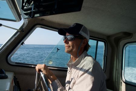 Capt. Greg Metzger drives his research boat out to sea. Concentrating on the temperature of the water, an important factor in the location of baby  white sharks, as he goes. (National Geographic/Brandon Sargeant)