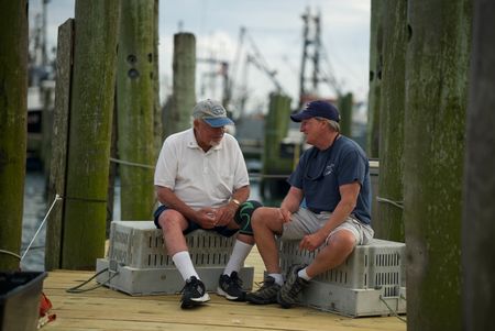 Jack Casey and Dr. Greg Skomal face each other while they talk on a pier in Martha Vineyard. (National Geographic/Brandon Sargeant)