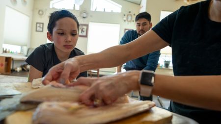 Ana Hoffman shows her nephew, Jaxon how to fillet a fish. (BBC Studios Reality Productions, LLC/Brian Bitterfeld)