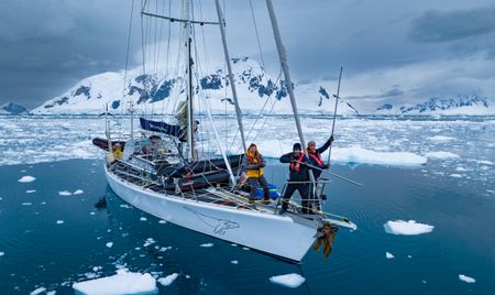 Bertie Gregory, Ralph Bower and Spencer Millsap posing for a photo whilst pushing icebergs out of the way of the boat with metal poles.  (credit: National Geographic/Bertie Gregory)