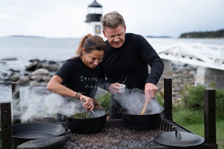 Rockland, ME - Chef Melissa Kelly (L) checks on her clams steaming under seaweed while Gordon Ramsay tends to his clam and lobster stew during the final cook. (Credit: National Geographic/Justin Mandel)