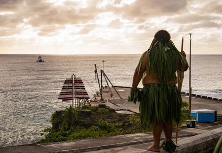 A Takalo warriors awaits the arrival of the National Geographic Pristine Seas expedition team. National Geographic Pristine Seas explored the marine ecosystem in Niue -a small island nation in the tropical Pacific. Local and international scientists surveyed the ocean to understand its health and biodiversity. Thanks to local leadership, traditional knowledge, and strong science, the country has been able to protect large swaths of its marine environment. (National Geographic/Nova West)