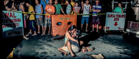 Manila, Philippines - A woman cradles the lifeless body of her partner at a crime scene. (Basilio Sepe)