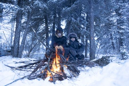 Skyler and Keenan DeWilde sit next to the fire to keep warm during the winter season. (BBC Studios Reality Productions, LLC/JR Masters)