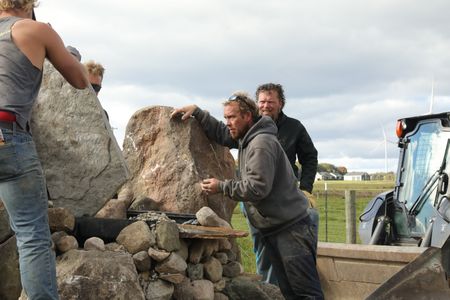 Seth Doble, Scott Brady, Ben Reinhold, and Charles Pol add large rocks to the Pol family farm's new pond to create a waterfall. (National Geographic)