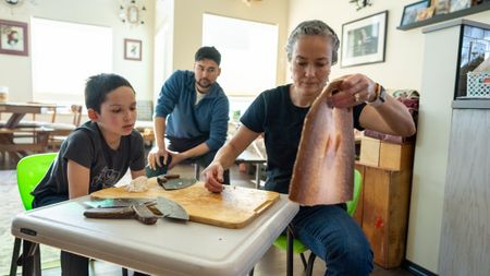 Ana Hoffman shows her nephew, Jaxon how to fillet a fish while her son Avery watches. (BBC Studios Reality Productions, LLC/Brian Bitterfeld)