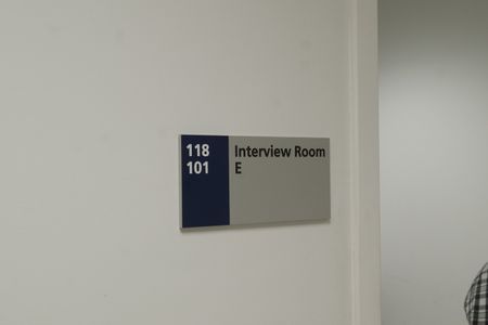 A plaque that reads "Interview Room E" is sitting attached to the wall of the JFK International Airport. (National Geographic)