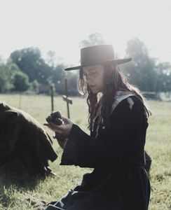 Geillis Duncan is kneeling over a grave, she is holding and examining the remains of a human arm. (Dash Productions Services LTD/Antoan Ivanov)