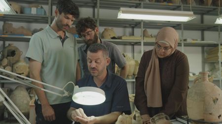 Ido Koch and his students looks over previously found artifacts at the Tel Aviv University in Tel Aviv, Israel. (Windfall Films/Nava Mizrahi)