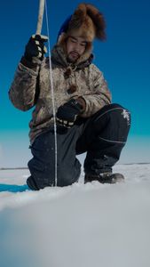 Gage Hoffman ice fishing in freezing temperatures. (BBC Studios Reality Productions, LLC/Brian Bitterfeld)