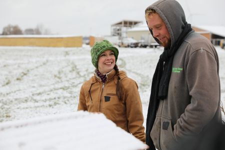 Beth Pol smiles while looking at Ben Reinhold by the Pol family's snowy beehives. (National Geographic)