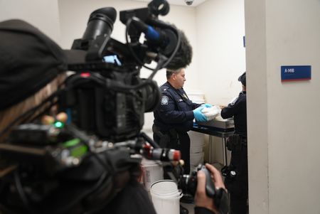 A cameraman films on as CBP Officer Bonilla and a fellow officer stack multiple packages of suspected narcotics onto a scale to weigh them  in Calexico, Calif. (National Geographic)