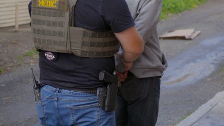 HSI Agent Nick places a suspect's hands behind their back after they were found holding a suspicious item in San Diego, Calif. (National Geographic)