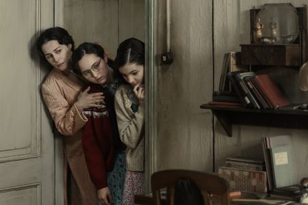 A SMALL LIGHT - Edith Frank, played by Amira Casar, and her daughters Margot, played by Ashley Brooke, and Anne, played by Billie Boullet, peer around the doorway in A SMALL LIGHT. (Credit: National Geographic for Disney/Dusan Martincek)