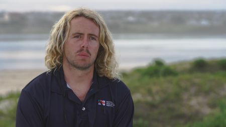 Lian Combrinck, contributor, talking to camera and reflecting upon witnessing Stuart Anderson being attacked by a shark and how him and another Sea Rescue volunteer helped aid Stuart on the beach before he was taken to hospital. (National Geographic)