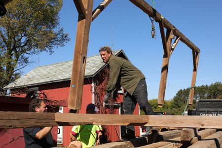 Charles Pol, Bill Klein, and Ben Reinhold help guide part of the old barn frame as it hangs from a telehandler. (National Geographic)