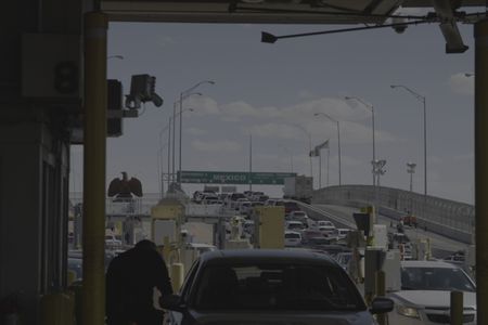 A CBP officer interacts with a traveler as multiple vehicles wait behind in line to cross the border at the El Paso port of entry in El Paso, Texas. (National Geographic)