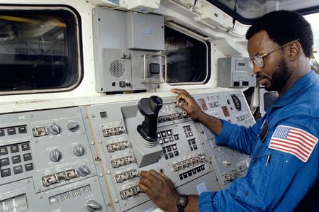 Astronaut Ronald E. McNair, one of NASA's three 41-B mission specialists, participates in a training session in the Shuttle one-g trainer in the Johnson Space Center's mockup and integrating laboratory on June 14, 1983.  He stands at the aft flight deck, where controls for the remote manipulator system (RMS) arm are located. (credit: NASA)