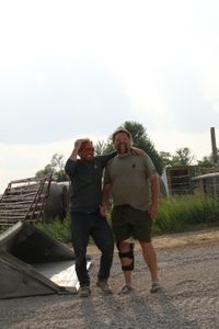 Ben Reinhold and Charles Pol, in a leg brace, share a laugh as they work on a swale to prevent flooding around the sheep hut. (National Geographic)